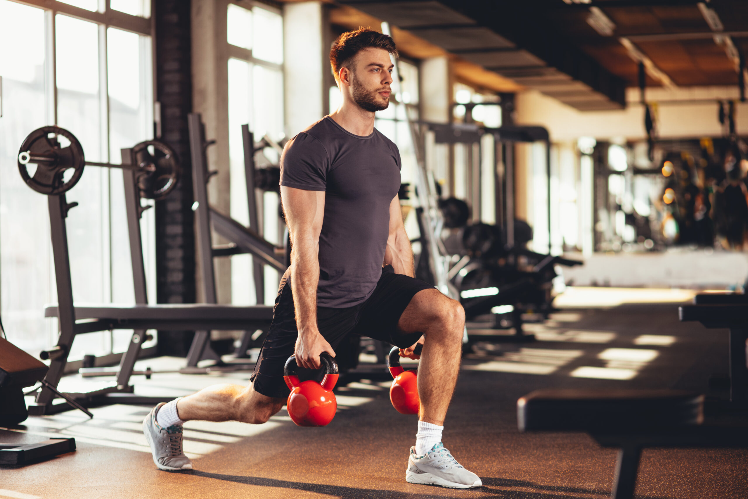 Handsome man legs workout with kettlebell in the gym - NinjaFitness