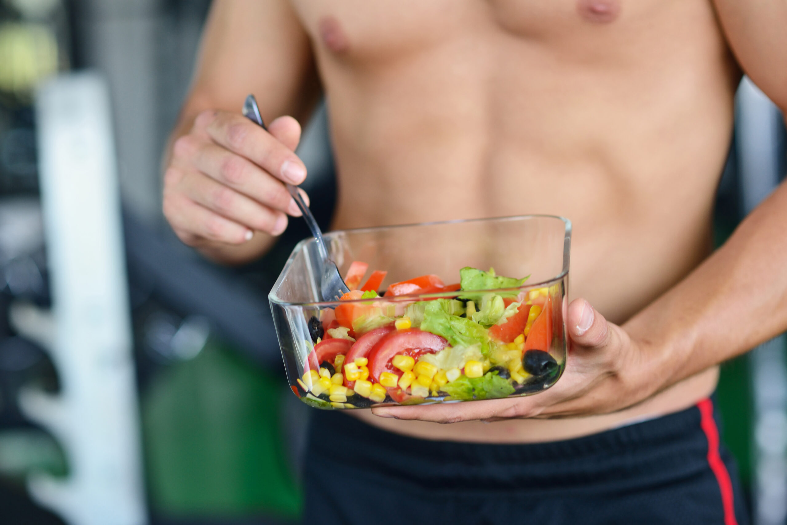 Powerful athletic man with great physique eating a healthy salad. - NinjaFitness Powerful athletic man with great physique eating a healthy salad.