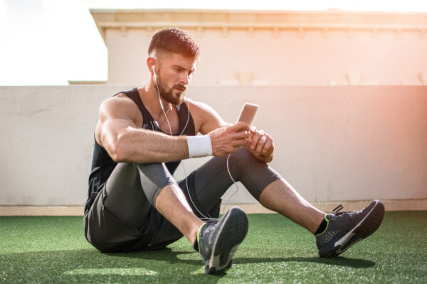 Young fit man using phone while having exercise break