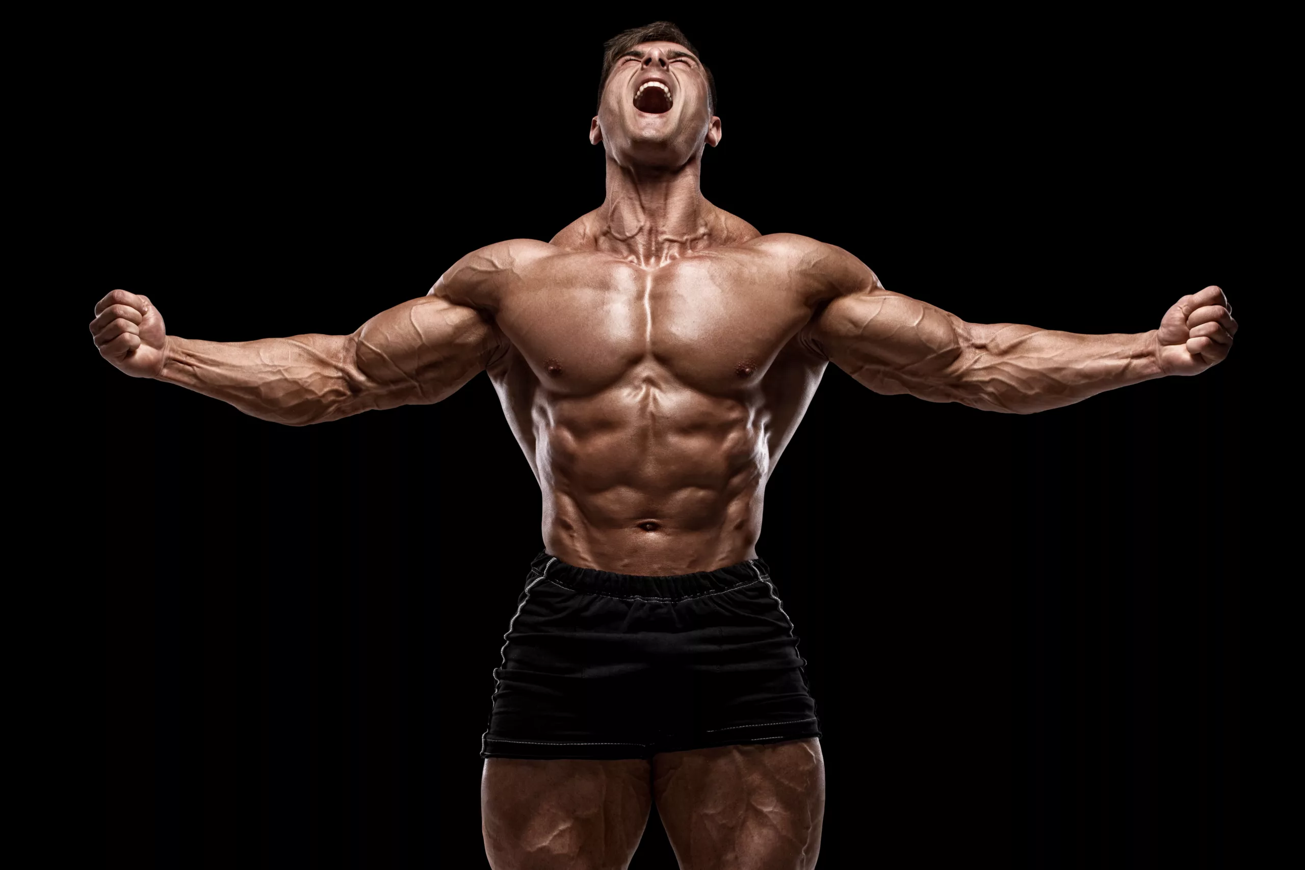 Muscular man showing muscles isolated on the black background S - NinjaFitness