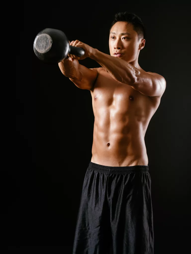 Photo of an Asian male exercising with a kettle bell doing metabolic strength conditioning