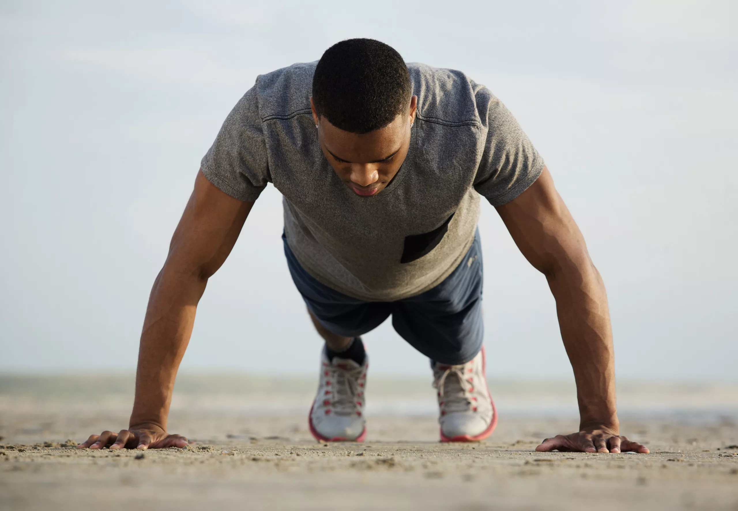 Fit young man doing push ups at the beach