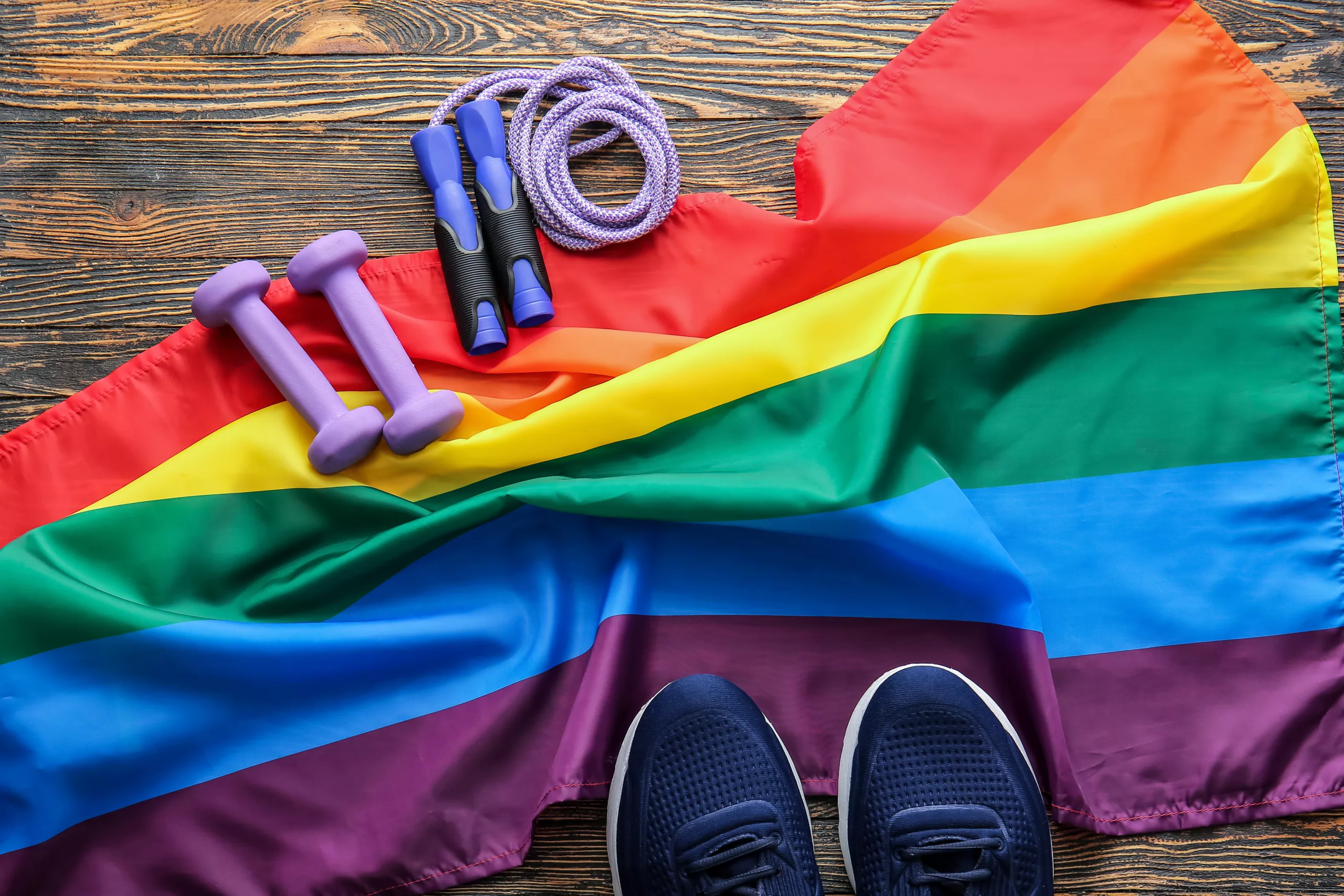 Sports equipment and rainbow LGBT flag on wooden background